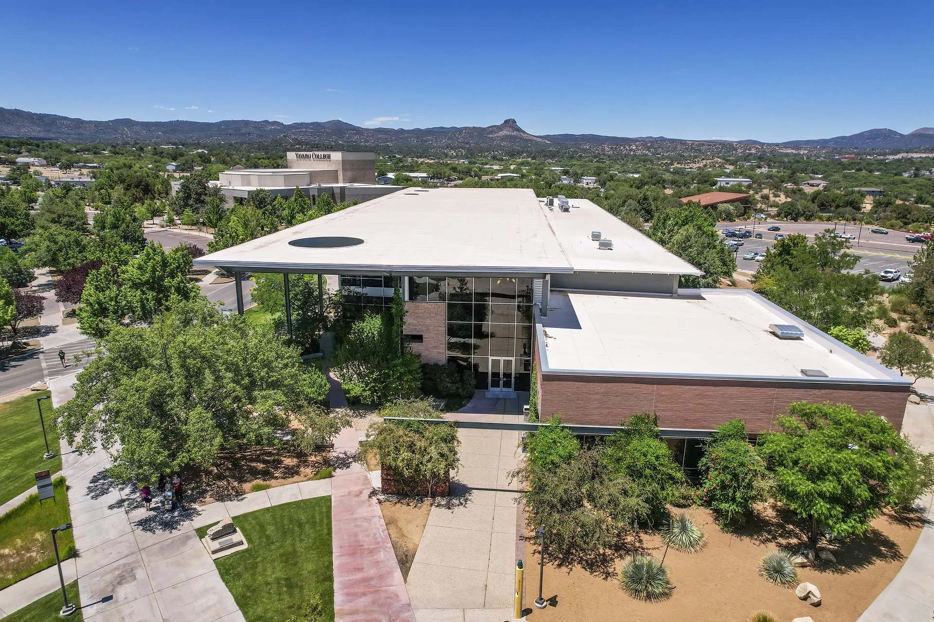 Aerial view of Yavapai College’s Prescott campus, with campus buildings, trees, and surrounding mountains.